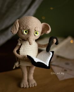 a crocheted rat holding an umbrella on top of a wooden table with lights in the background