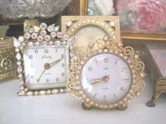 there are three clocks on the table next to each other, one is white and gold