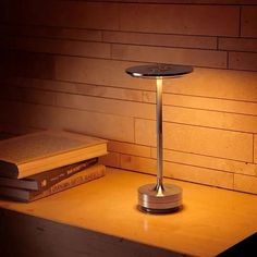 a table lamp sitting on top of a wooden desk next to a stack of books