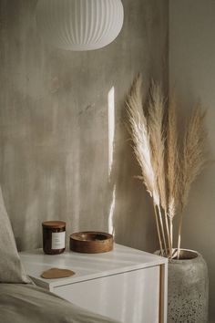 a bedroom with a bed, nightstand and plant on the side table in front of it