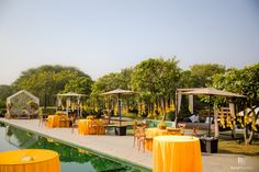 an outdoor dining area next to a pool with tables and umbrellas set up around it