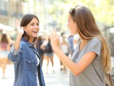 two young women standing in the middle of a busy street giving each other high fives