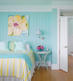 a bedroom with blue and yellow walls, striped bedspread, white nightstands and a painting on the wall