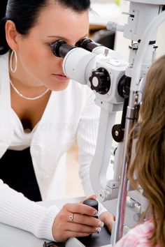 a woman looking through a pair of glasses at another person with an eye chart in front of her