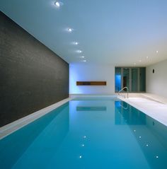 an indoor swimming pool with blue water in the middle and white walls on either side