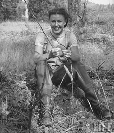 black and white photograph of a woman sitting on the ground with her fishing rod in hand