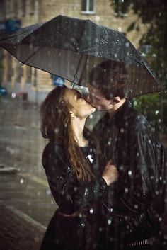 a man and woman kissing under an umbrella in the rain on a rainy day with words written below