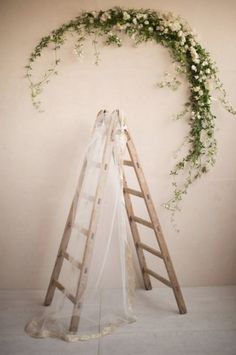 an image of a ladder decorated with flowers and greenery on the side of a wall