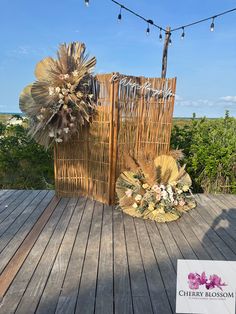 two baskets with flowers on them sitting on a wooden deck next to string lights and trees