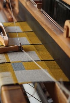 a close up view of a weaving machine with yarn on the sides and wood spools