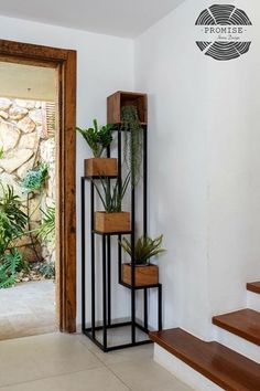 three planters are stacked on the wall next to some wooden steps and a door