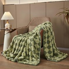 a green blanket sitting on top of a chair next to a lamp