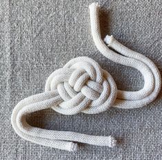 white rope on the floor with knoted ends and two pieces of string attached to it