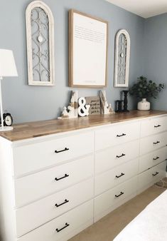 a white dresser with drawers and pictures on the wall