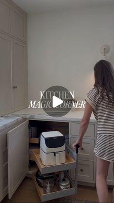 a woman standing in a kitchen next to an open cabinet