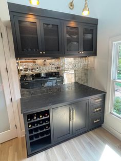 a kitchen with black cabinets and grey counter tops, wine glasses on the cabinet doors