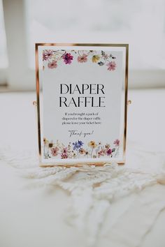 a paper raffle sign sitting on top of a white table cloth covered bedding