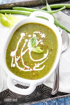 a white bowl filled with green soup on top of a table