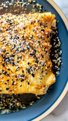 a piece of meat covered in sesame seeds and seasoning on top of a blue plate