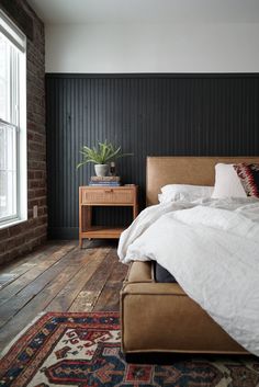 a bed with white sheets and pillows on top of it next to a wooden table