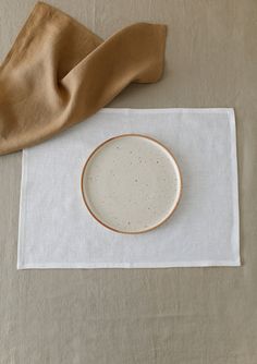 a white and brown plate sitting on top of a table next to a tan cloth