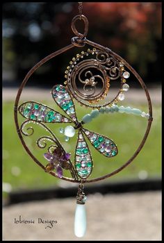 a metal wind chime with dragonflys and beads on it