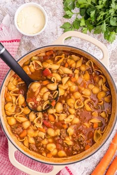 a pot filled with pasta and vegetables next to some parmesan cheese on the side