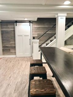 an empty room with two stools next to a table and stairs in the background