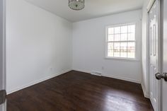 an empty room with hard wood floors and white walls