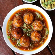 some food is in a white bowl on a wooden table next to bowls of peas