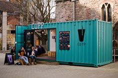 some people sitting on steps near a large blue container with the word cupp written on it