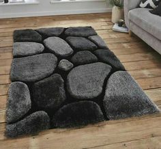 a living room with wooden floors and a gray rug on top of the wood floor