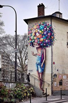 a painting on the side of a building with a woman holding a bunch of balloons