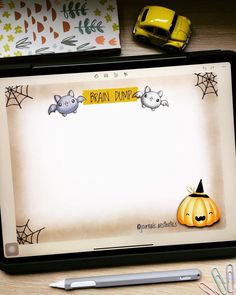 a tablet with an image of cats and pumpkins on it, next to pens and markers