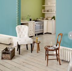 a living room filled with furniture next to a wall painted in blue and green colors