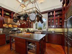 a large kitchen with lots of pots and pans hanging from the ceiling over the island