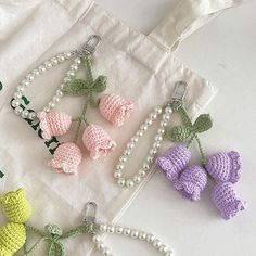 four crocheted keychains with bows and pearls on them, all in pastel colors