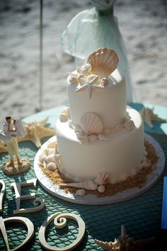 a wedding cake with seashells on it and the word love spelled out in large letters