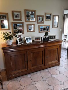 a large wooden cabinet with pictures on the wall above it and a potted plant