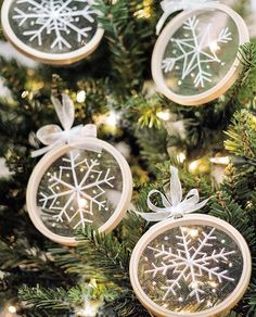 three snowflake ornaments are hanging from a christmas tree with lights on the branches