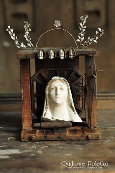 a statue of the virgin mary in a wooden box with bells on it's head