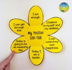 a hand holding up a yellow flower with words on it