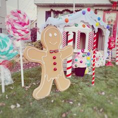 a gingerbread man is standing in front of some candy canes on the lawn