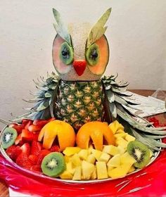 a bowl filled with fruit and an owl figurine sitting on top of it