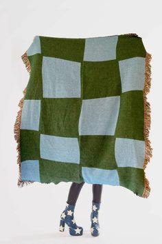 a woman is holding up a green and blue checkered blanket with stars on it