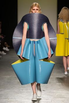 a model walks down the runway in blue and yellow dresses with large circular shapes on them