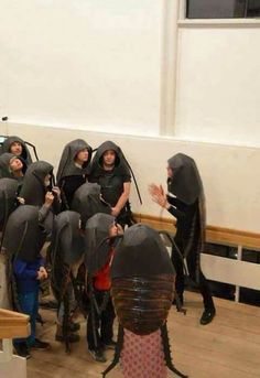 a group of people in black hoods standing next to each other on a wooden floor