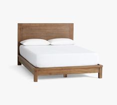 a bed with white sheets and pillows on it's headboard, made from solid wood