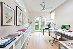 a home office with white walls and wooden floors, along with pictures on the wall