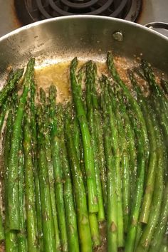 asparagus are being cooked in a pan on the stove top with oil and seasoning